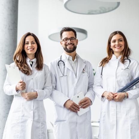 Drei Ärzte lächeln nebeneinander in die Kamera
